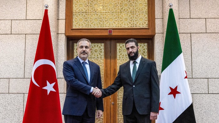 Turkey’s foreign minister Hakan Fidan (L) is received by Hayat Tahrir al-Sham (HTS) leader Abu Mohammad al-Jolani